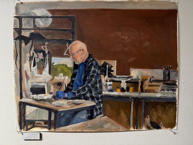 oil painting of old man working at desk in cluttered studio. He is very focused and wearing flannel.