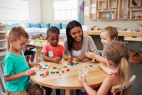 teacher with young children at a play table